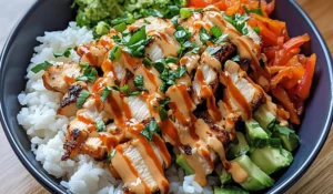 A flavorful Bang Bang Chicken Bowl topped with fresh vegetables and spicy sauce