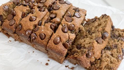 Sliced healthier chocolate chip banana bread on a wooden board.